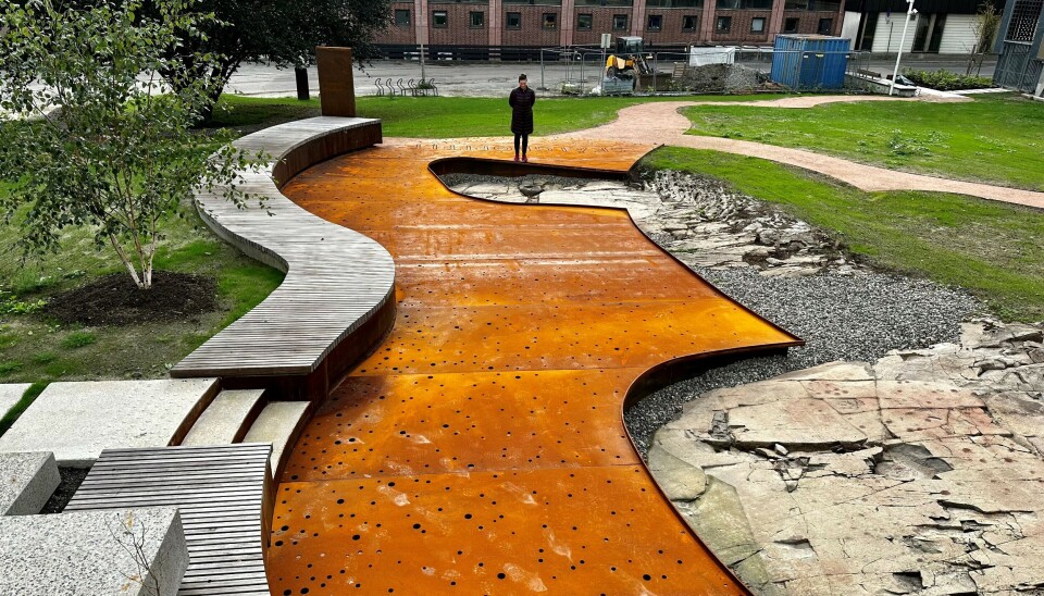 BENK OG SKÅLGROPEFELT: I parken er det verneverdige fornminner med to skålgropfelt som er hjertet i den nye utformingen av parken. Her er det tilrettelagt for å vise fram denne unike historien. BENK: Møbleringen er utformet som en integrert del av landskapsarkitekturen og danner et nedsenket oppholdssted rundt de to skålgropfeltene. Her er det sokkel i cortenstål og trespiler på tvers.(Foto: Bjørbekk & Lindheim)