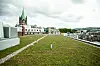Grønt tak på bybygning med kirketårn og boliger i bakgrunnen.