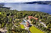 Flyfoto av et ferieanlegg omgitt av skog ved en innsjø.
